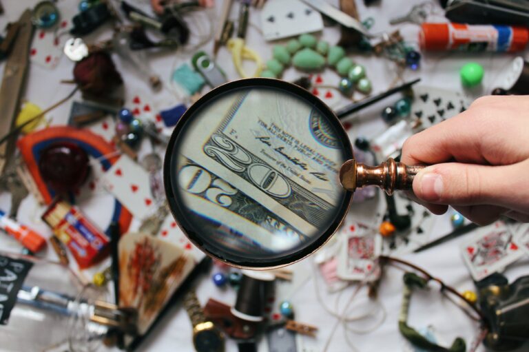 Magnifying glass focusing on money with random items in the background.