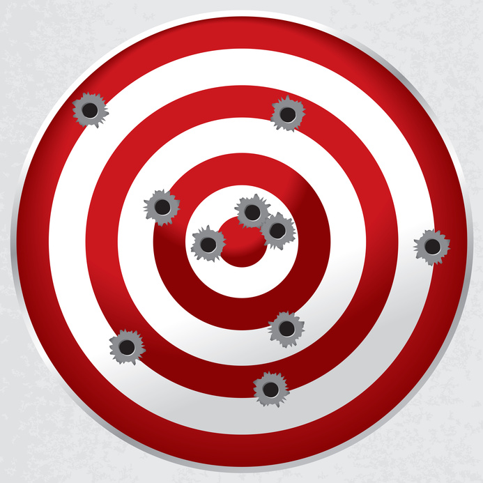 Red and white shooting range target shot full of bullet holes